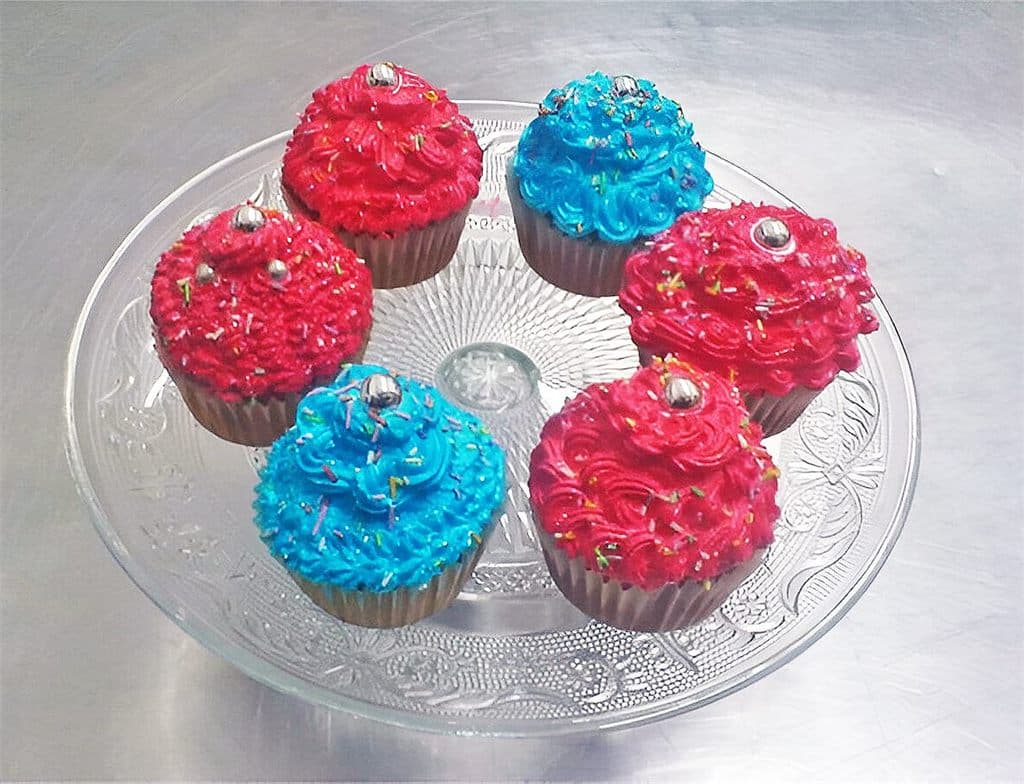Cupcakes con crema roja y azul sobre una bandeja de cristal, elaborados en Dulces Caprichos en As Pontes