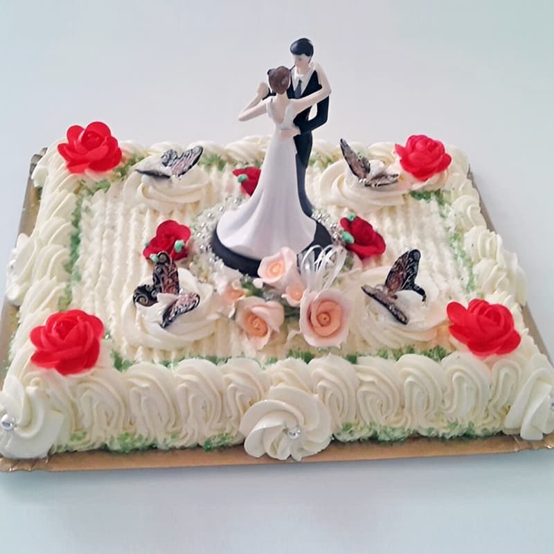 Tarta de boda rectangular de nata con rosas y figuras de novios, elaborada en Dulces Caprichos en As Pontes