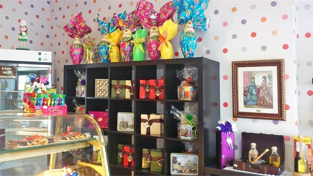 Interior de la pastelería Dulces Caprichos en As Pontes, con estantería de dulces y regalos y vitrina de pasteles